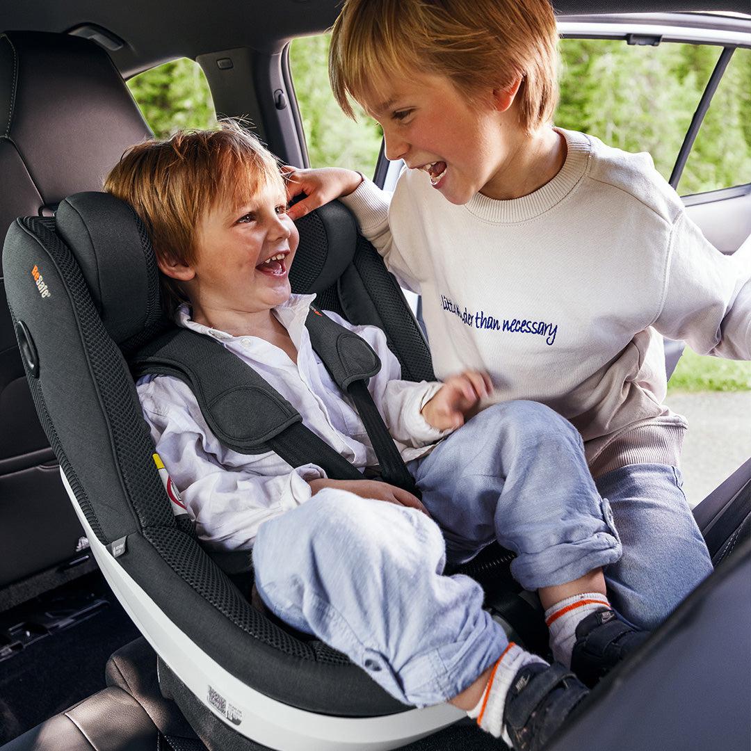 Toddler strapped in to a BeSafe Beyond 360 Car Seat happily laughing with his brother.
